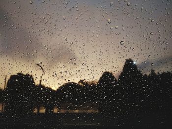 Close-up of wet window against sky at dusk
