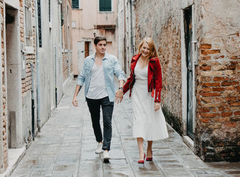 Full length of couple walking in alley against buildings