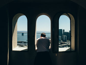 Rear view of woman standing by sea against clear sky