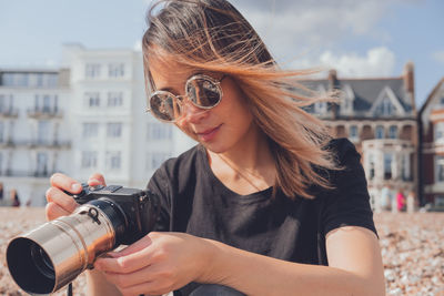 Asian woman taking photos with her camera on the beach