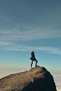 Man standing on rock against sky