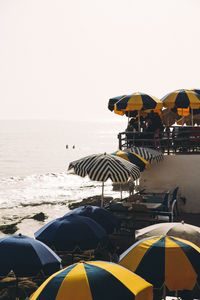 Beach umbrellas by sea against clear sky