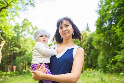 Portrait of mother and daughter standing against trees