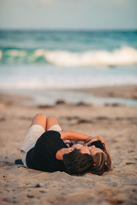 Low section of woman relaxing at beach