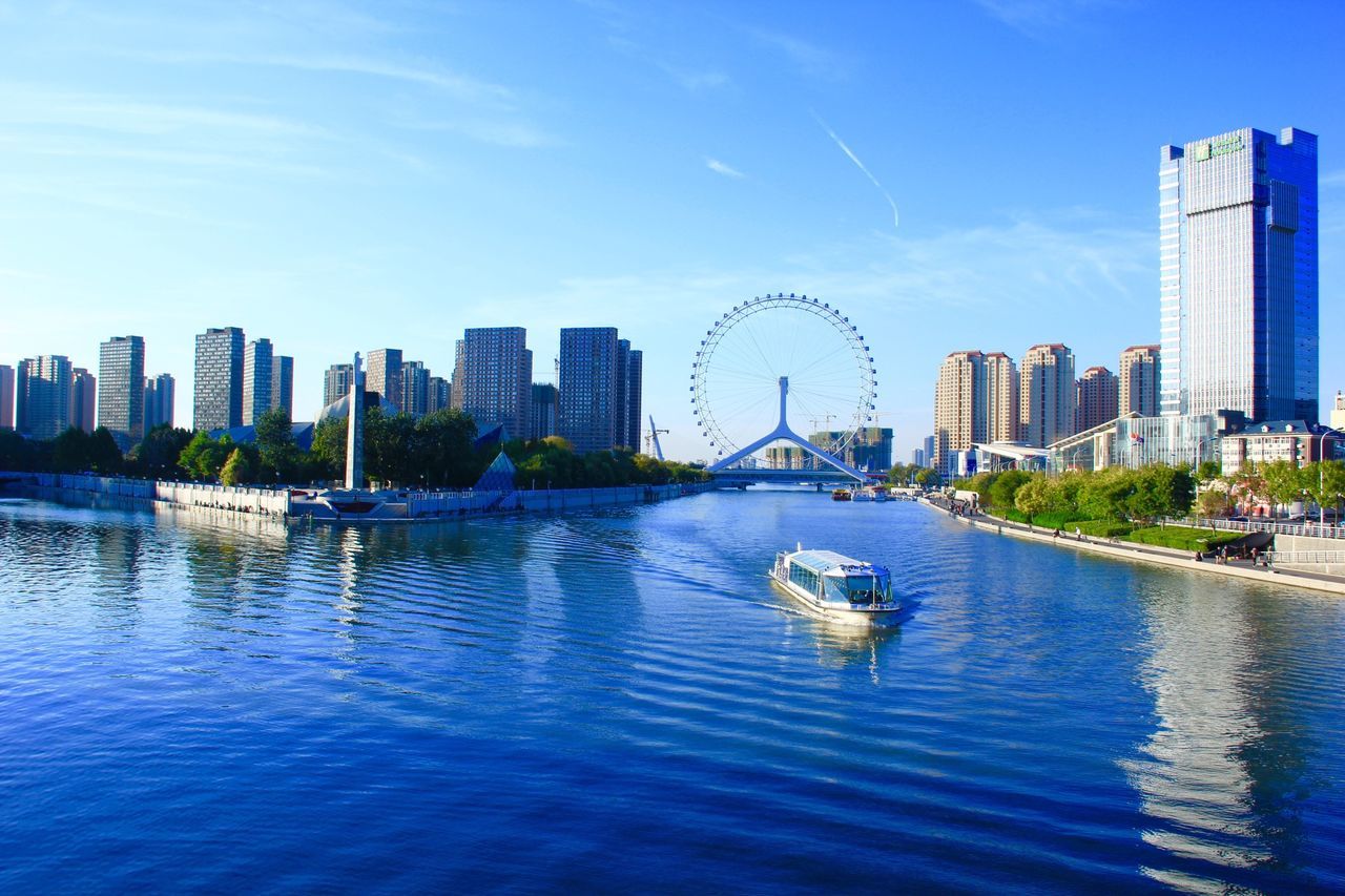 architecture, city, built structure, building exterior, water, waterfront, river, skyscraper, cityscape, sky, capital cities, modern, ferris wheel, transportation, tower, urban skyline, tall - high, travel destinations, blue, famous place