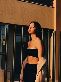 Woman looking away while standing against window