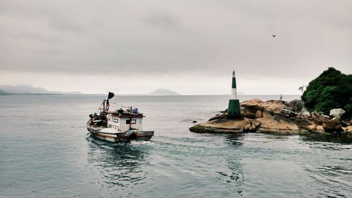 High angle view of boat in sea by rock formations against sky