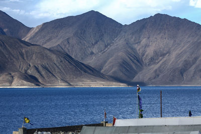 Man standing on sea by mountains against sky