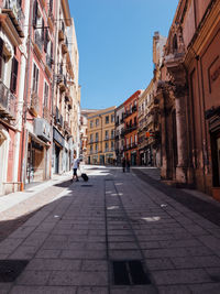 Man walking on street in city against clear sky