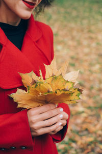 Midsection of woman holding autumn leaves