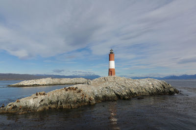 Lighthouse by sea against sky