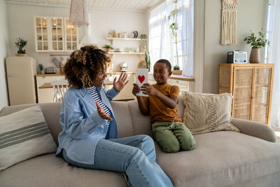 Mother and daughter sitting on sofa at home