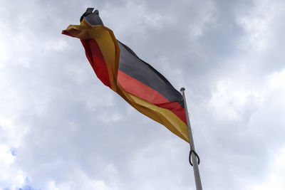 Spain flag at a flagpole moving in the wind against the sky