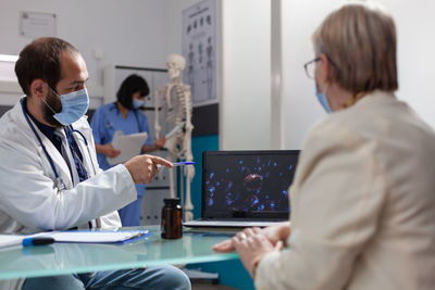 Doctor wearing mask while talking to patient in clinic