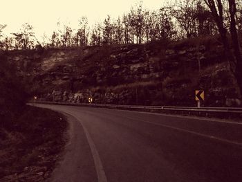 Road by trees against sky