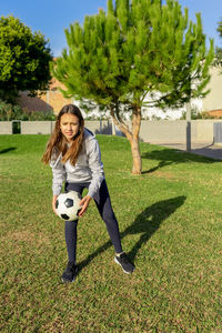 Full length of girl playing with soccer ball at park