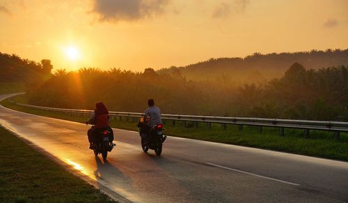 People walking on road at sunset