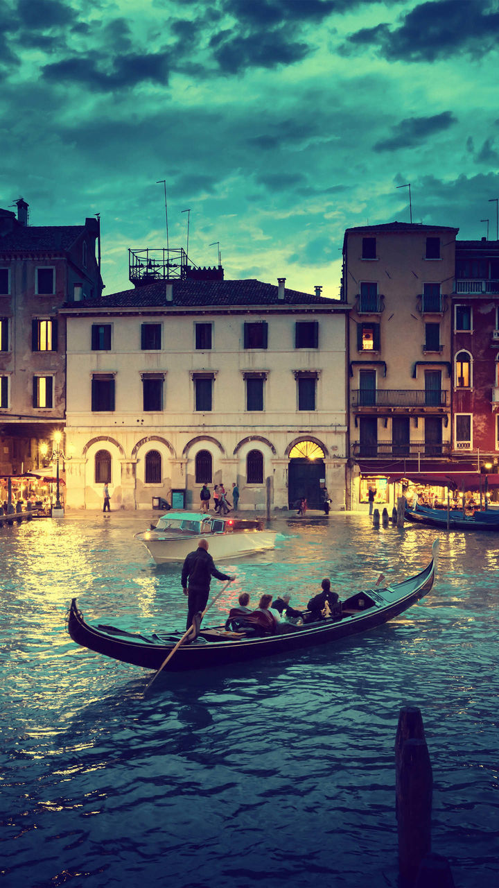 gondola - traditional boat, architecture, canal, transportation, gondolier, building exterior, nautical vessel, built structure, gondola, men, real people, mode of transport, oar, travel, day, outdoors, rowing, travel destinations, water, sitting, standing, sky, one person, adult, people