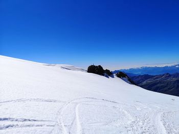 Scenic view of snow covered mountains against clear blue sky