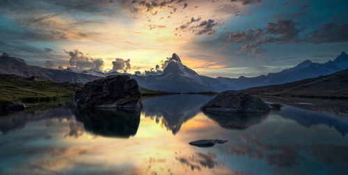 Scenic view of lake and mountains against sky during sunset