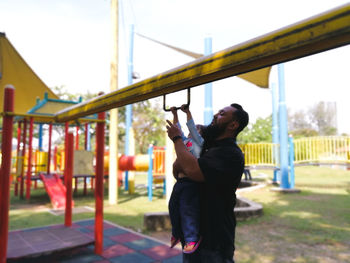Man carrying daughter playing at playground