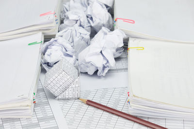 High angle view of crumpled paper balls with model house on financial documents