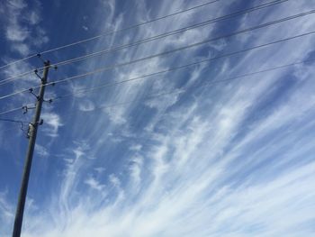 Low angle view of power lines against cloudy sky