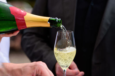 Closeup of a champagne bottle pooring champagne into a champagne flute against a blurred person