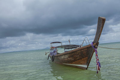 Fishing boat moored on sea against sky