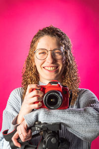 Portrait of young woman holding camera