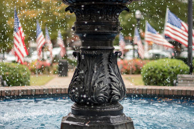 Close-up of fountain against american flags in park