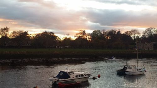 Boats moored in lake against sky during sunset