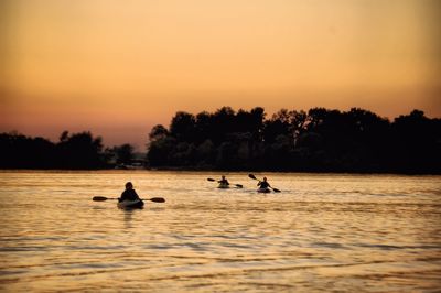 Silhouette of people rafting on river