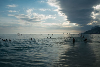 Silhouette people on beach against sky during sunset