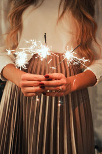 Midsection of woman holding sparklers