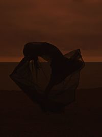 Side view of silhouette woman on beach during sunset