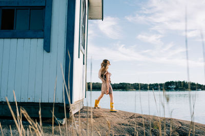 Woman standing by lake against sky