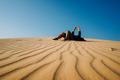 People on sand dune in desert against clear blue sky