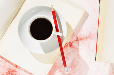 Directly above shot of coffee with books and pencil on table