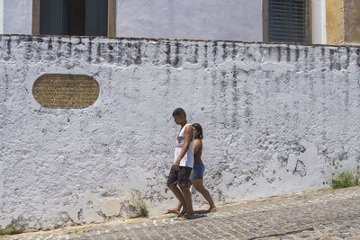 Rear view of friends standing against wall