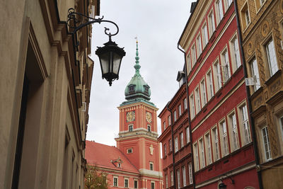 Low angle view of street light amidst buildings against sky