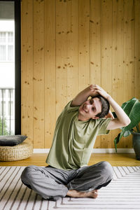 Smiling man exercising while sitting cross-legged at home