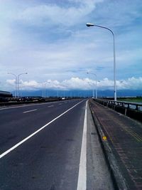 Empty road against cloudy sky