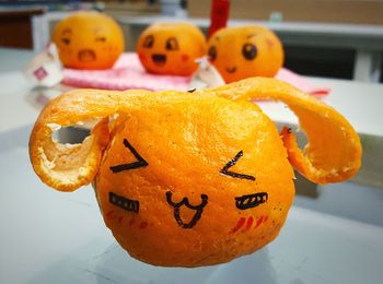Close-up of anthropomorphic faces drawn on oranges at table