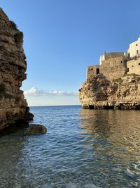Sea by buildings against clear blue sky
