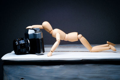 Close-up of wooden human figurine with camera on table
