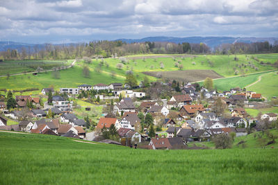 Scenic view of agricultural field by houses against sky