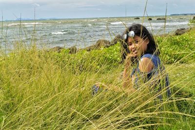 Portrait of girl sitting at grassy beach