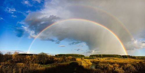 Scenic view of double rainbow over countryside landscape