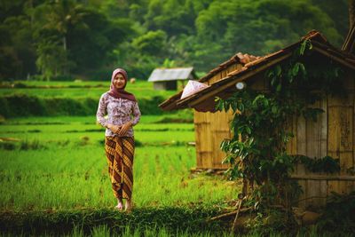 Portrait of young woman wearing hijab standing on grassy field